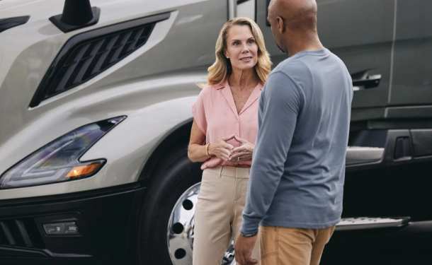 Volvo sales employee and customer talking while standing in a truck lot.